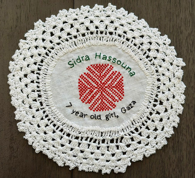 Tatreez pattern of a carnation embroidered on a doily with the name of Sidra Hassouna , a 7-year-old girl from Gaza. The name has been embroidered in English.