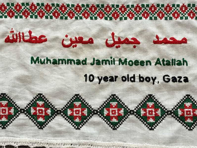 Tatreez patterns of of a wreath and an amulet embroidered on a doily with the name of Muhammad Jamil Moeen Atallah, a 10-year-old boy from Gaza. The name has been embroidered in English and Arabic.