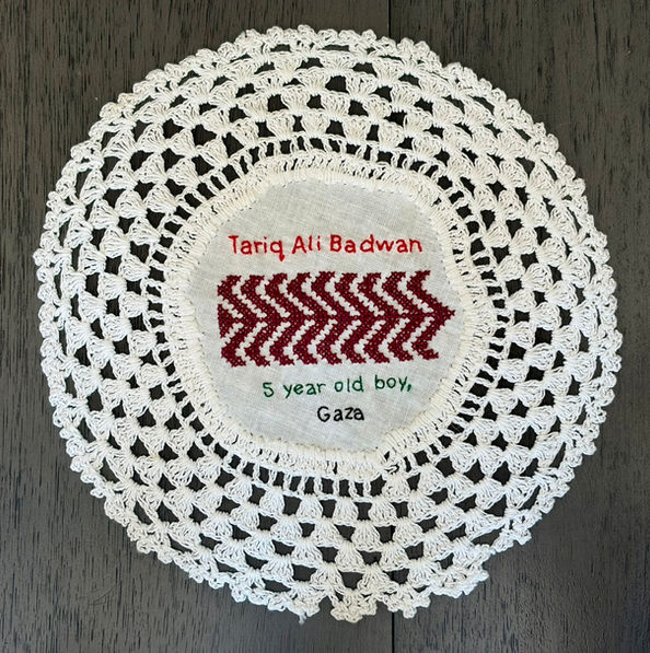 Tatreez pattern of a palm tree embroidered on a doily with the name of Tariq Ali Badwan, a 5-year-old boy from Gaza. The name has been embroidered in English.