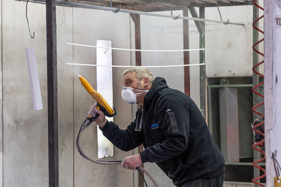 Technician applying white powder coating in spray booth at Ashburton Powder Coating