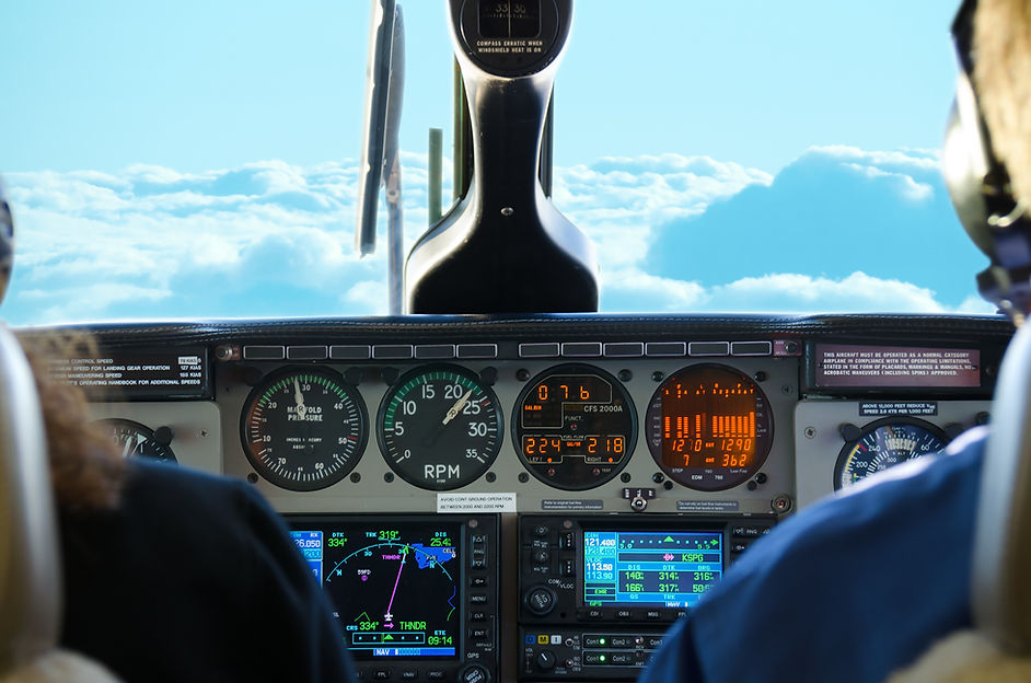 Small twin turbo engine airplane cockpit view while in flight with gauges lit up and fluff