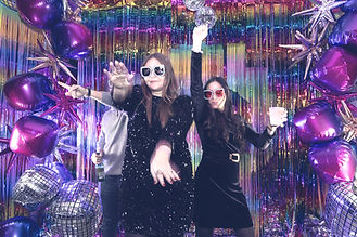 Partygoers in front of glitzy step and repeat at holiday party in New York City.