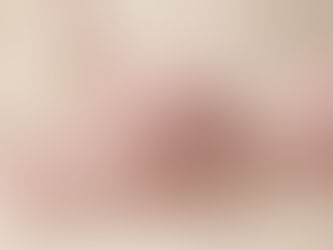 Primer plano de un brasier clásico de color rosa pálido con detalles de encaje floral en las copas, recostado sobre una superficie suave.