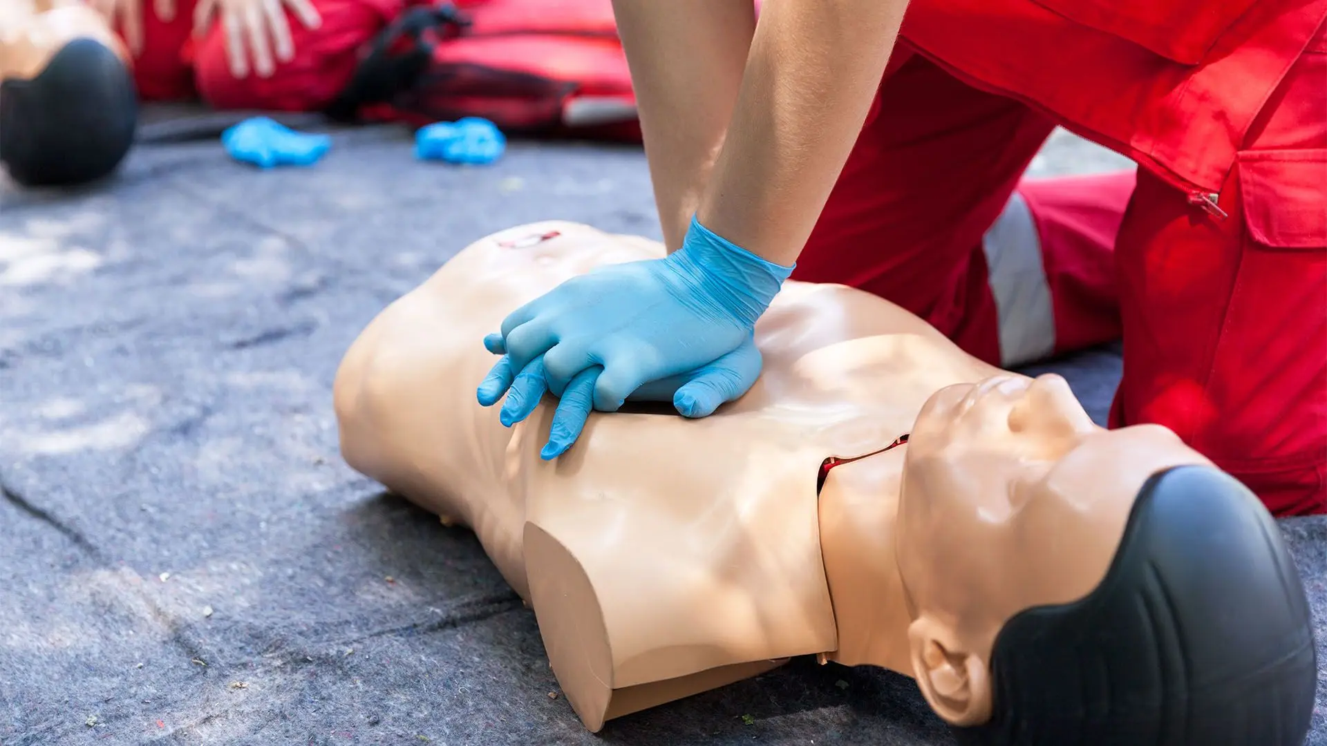 Practicing CPR on a mannequin at an outdoor first aid course.