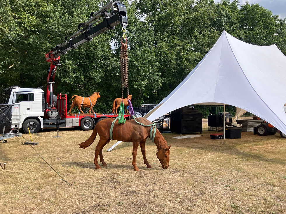 Roestkleurige paardensculpturen bij een eventweide