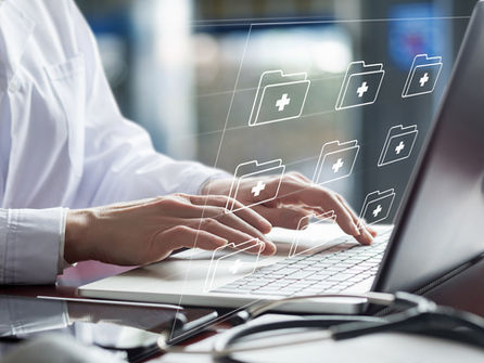 Doctor working on laptop with electronic documents