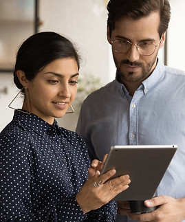 Close up diverse colleagues using tablet together, discussing online project, smiling Indi