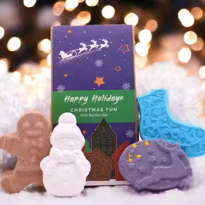 4 bathbombs infront of the gift packaging with a christmas vibe background