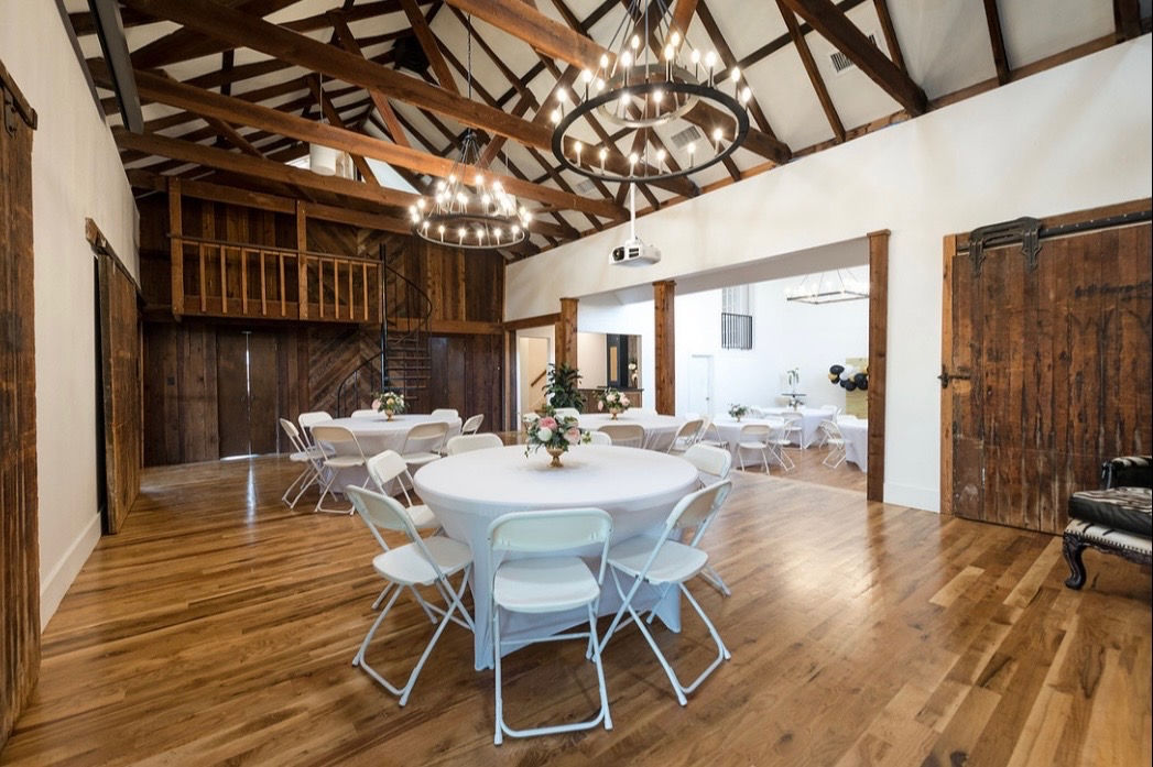 Rustic event rental space with set tables and chandeliers