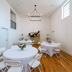 Intimate event rental room with tables, chairs, and balloons.