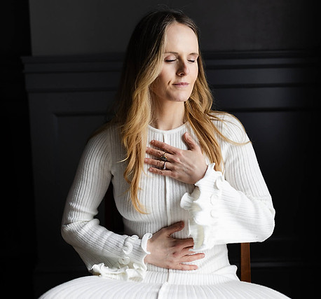 Woman meditating with hands on chest and abdomen for grounding breathwork.