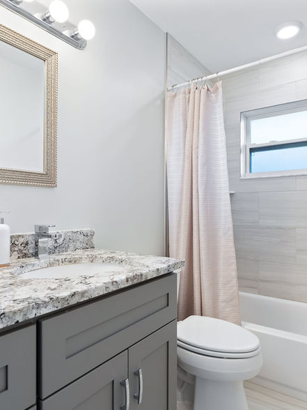 Modern and updated guest bathroom with granite countertop and grey vanity
