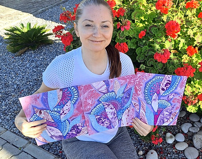 Artist holding a mixed media triptych on paper in pink and purple shades