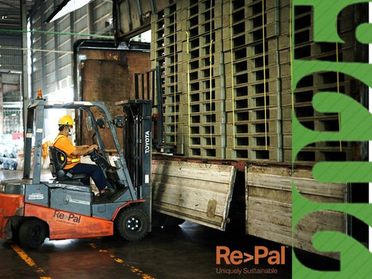 Forklift operator loading recycled plastic pallets by Re>Pal onto a truck inside a warehouse.