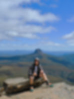Adam Woodard sitting on a rock atop Cradle Mountain, Tasmania