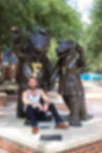 Adam Woodard sitting under gator mascot statues at the University of Florida