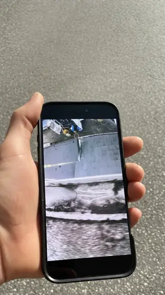 Hand holding phone with image of gutter