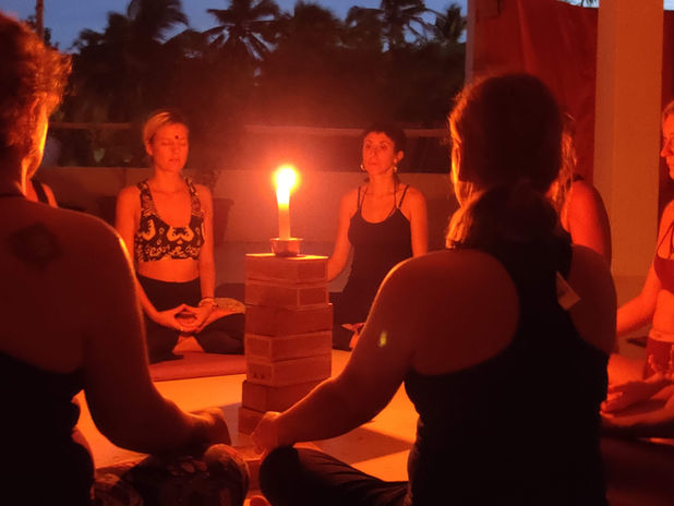 Students practising candle meditation during yoga teacher training