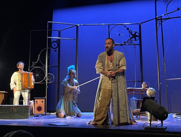 Archimede, la Solitudine di un genio, è lo spettacolo che andrà in scena presso la sala Bobbio del teatro La Contrada. L'attore Mario Incudine al centro in piedi girato leggermente verso sinistra, indossa una camicia morbida beije e collane lunghe al collo. A completare l'abbigliamento, un lungo senza maniche. Dietro a lui, un soldato connelmo e piume, inginocchiato. In ultimo piano un musicista seduto con una fisarmonica. Sfondo blu e struttura con ruote appese.