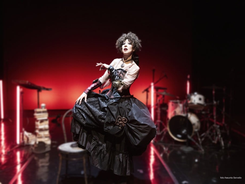 L'inferiorità mentale della donna, è lo spettacolo che andrà in scena presso la sala Bobbio del teatro La contrada in occasione della Stagione del 50esimo anniversario. La protagonista è Veronica Pivetti ed è presente nell'immagine. La donna sembra danzare con eleganza verso sinistra. Indossa un abito maestoso nero e beige. La gonna è a palloncino. Sullo sfondo un leggio e una batteria. Luci rosse neon soffuse. Background nero