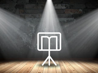 Teatro a Leggìo per gli associati agli Amici della Contrada. Una stanza con a centro un leggìo. pavimento in legno, muro in mattoni grigi. Riflettori da palco.