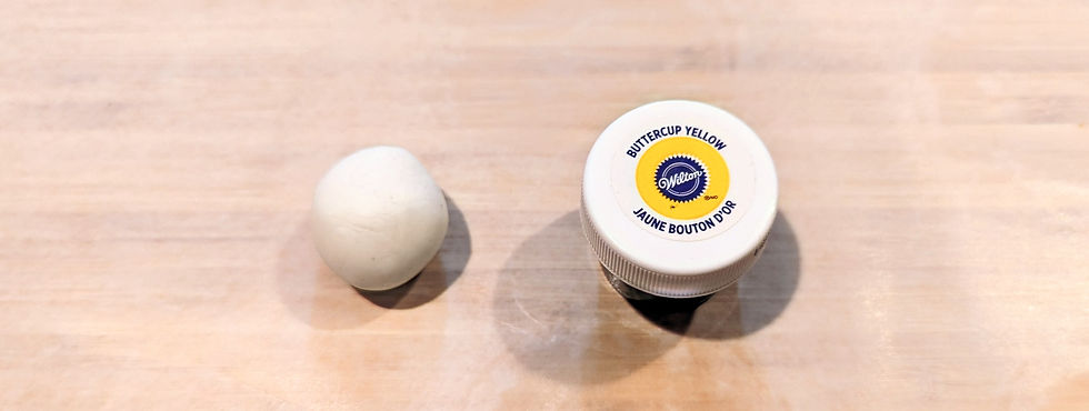 Rolled ball of white dondant sitting beside a small container of Wilson's Buttercream Yellow fondant dye.