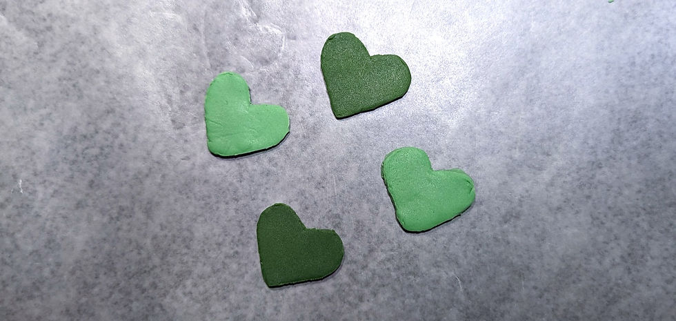 Four green fondant heart shaped cutouts.