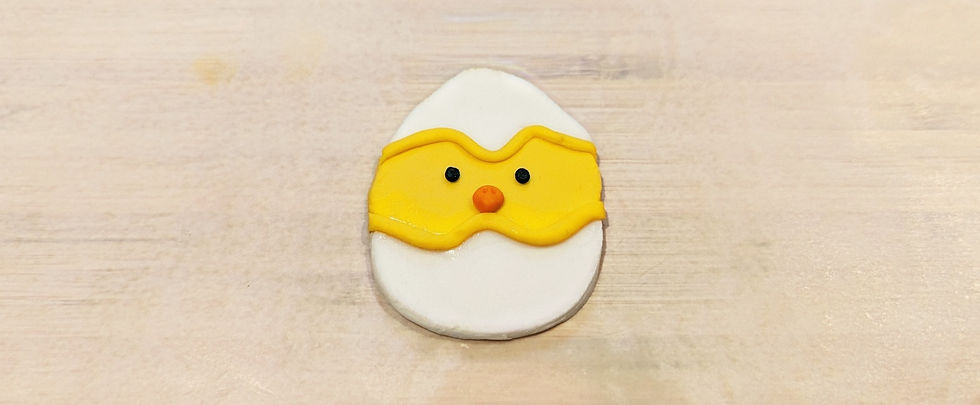 Shape of a baby chick face peaking out of an eggshell made of fondant.