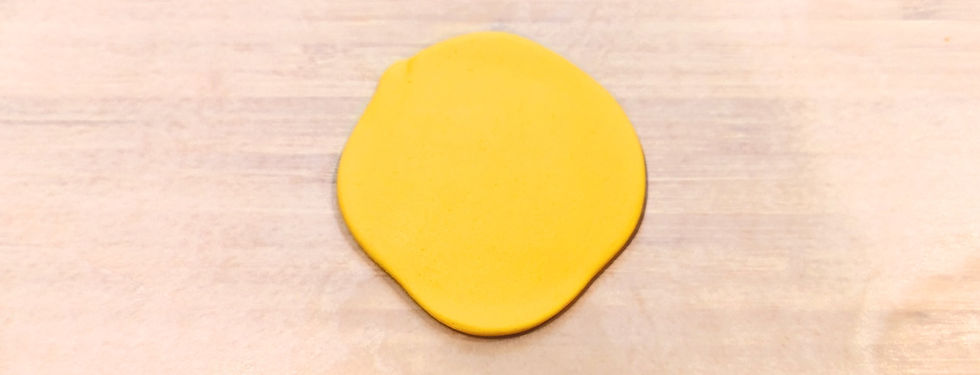 A piece of yellow fondant rolled out flat on a flat surface.