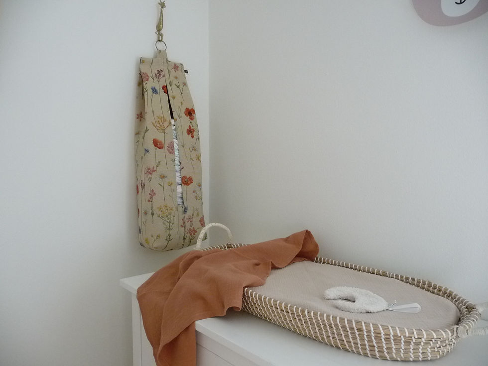 Babykamer met een luieropbergzak van bloemenprint hangend aan de muur naast de commode.