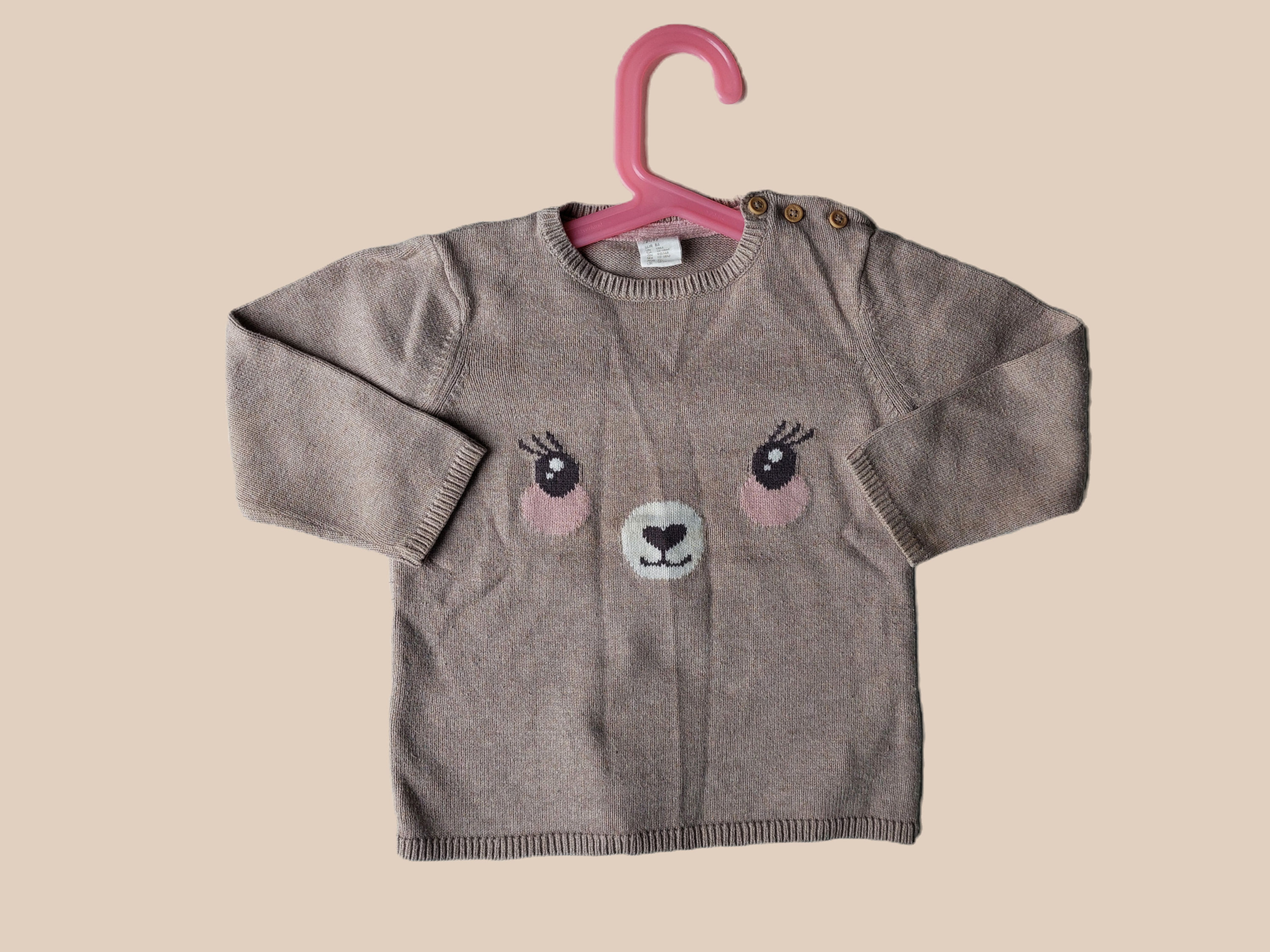 Beige genser med øyner, nese og munn