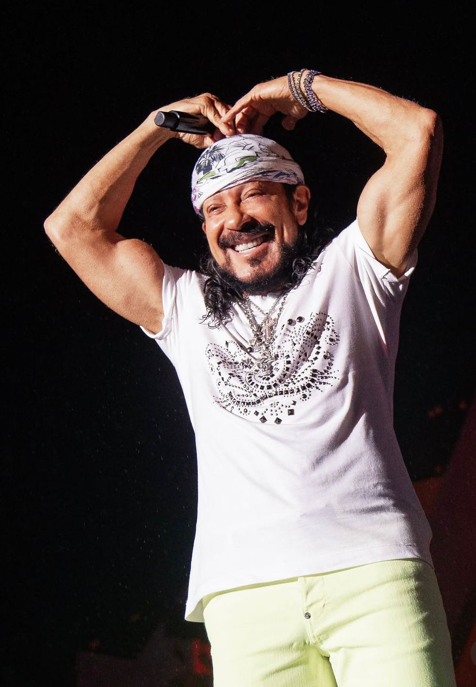 o cantor bell marques fazendo o gesto de coração com os braços acima da cabeça