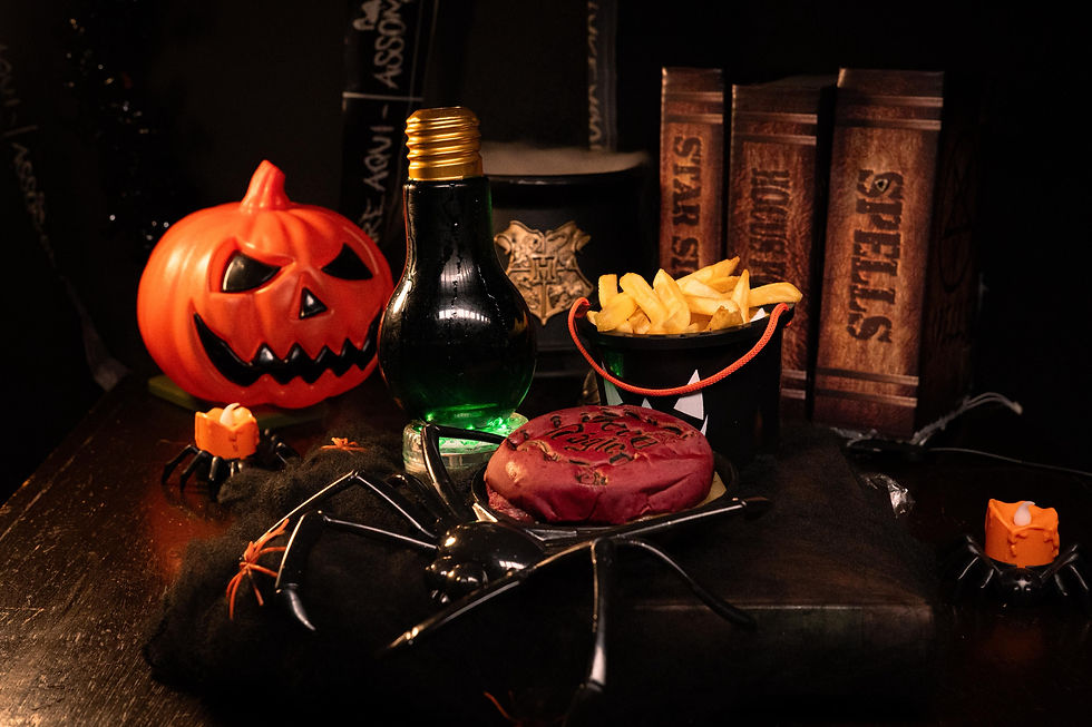 hamburguer em cima de um prato em formato de aranha com vários outros adereços de halloween ao redor