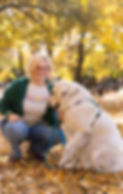 A woman kneels on the ground with a white dog