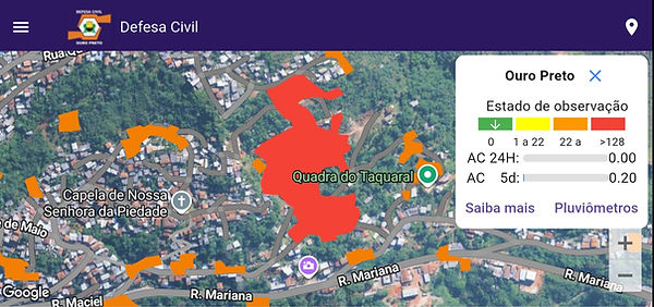 Captura de tela do aplicativo da Defesa Civil de Ouro Preto mostra mapa de áreas de risco, em tons laranja e vermelho. Um painel informa que o município está em estado de observação e exibe dados de monitoramento de chuva.