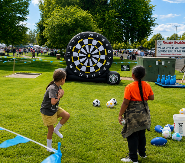 Boys throwing baseballs at giant inflatable velcro dartboard at outdoor community event
