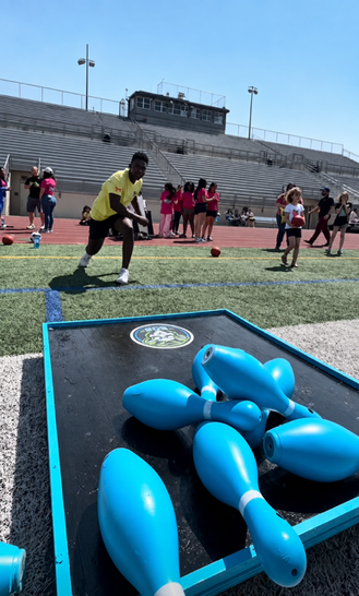 Boy knocking down pins at pin challenge game during outdoor community event