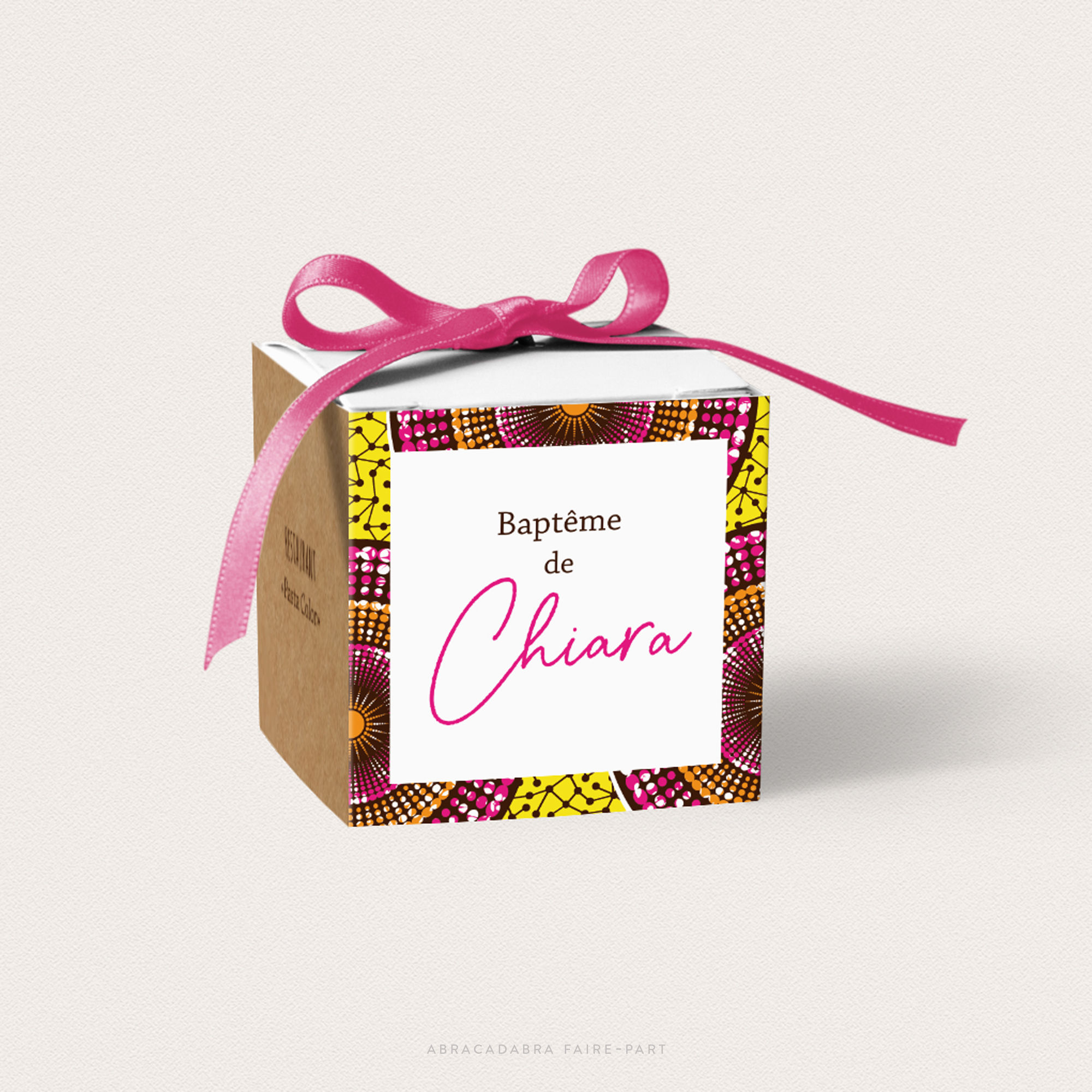 Boîte à dragées baptême cubique avec fond kraft et motif africain, ruban rose sur le dessus, vue face