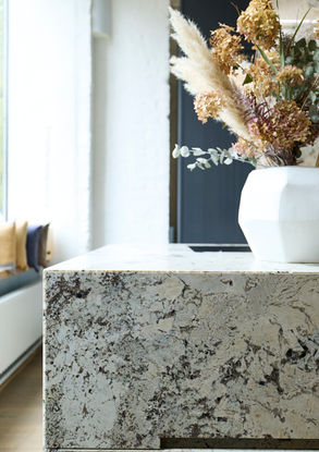 Neue Ausstellungsküche im Küchenatelier Hamburg: Transluzenter Granit ‘White Tiger’ mit hinterleuchteter Rückwand und Echtholzfronten in Davos. Die massive Insel kombiniert Licht, Struktur und natürliche Materialien zu einem modernen Küchen-Statement.