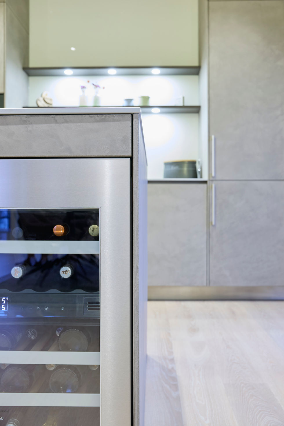 Moderne Küche mit „Tokio“-Fronten aus Beton, Keramikarbeitsplatte in Calce Grigio und Bocci-Leuchten über dem Tresen.