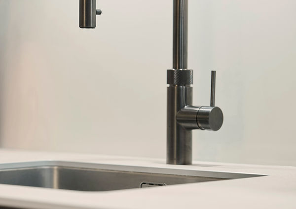 Moderne Küche mit „Tokio“-Fronten aus Beton, Keramikarbeitsplatte in Calce Grigio und Bocci-Leuchten über dem Tresen.