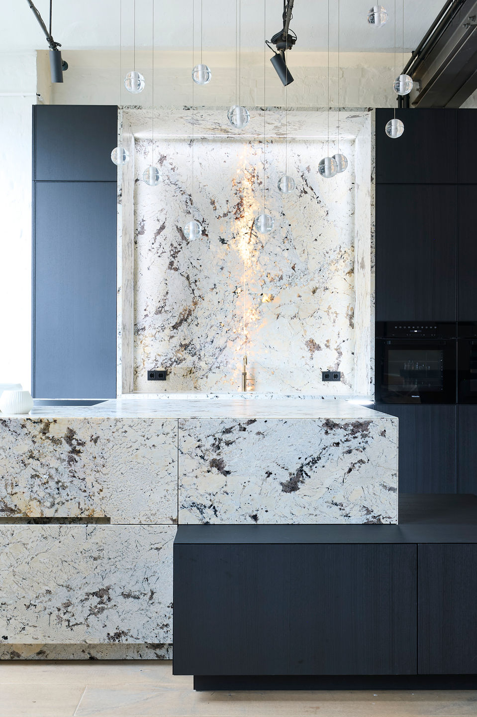 Massive Naturstein Kücheninsel White Tiger in eggersmann Designküche im Küchenatelier Hamburg mit hochwertigen Materialien.