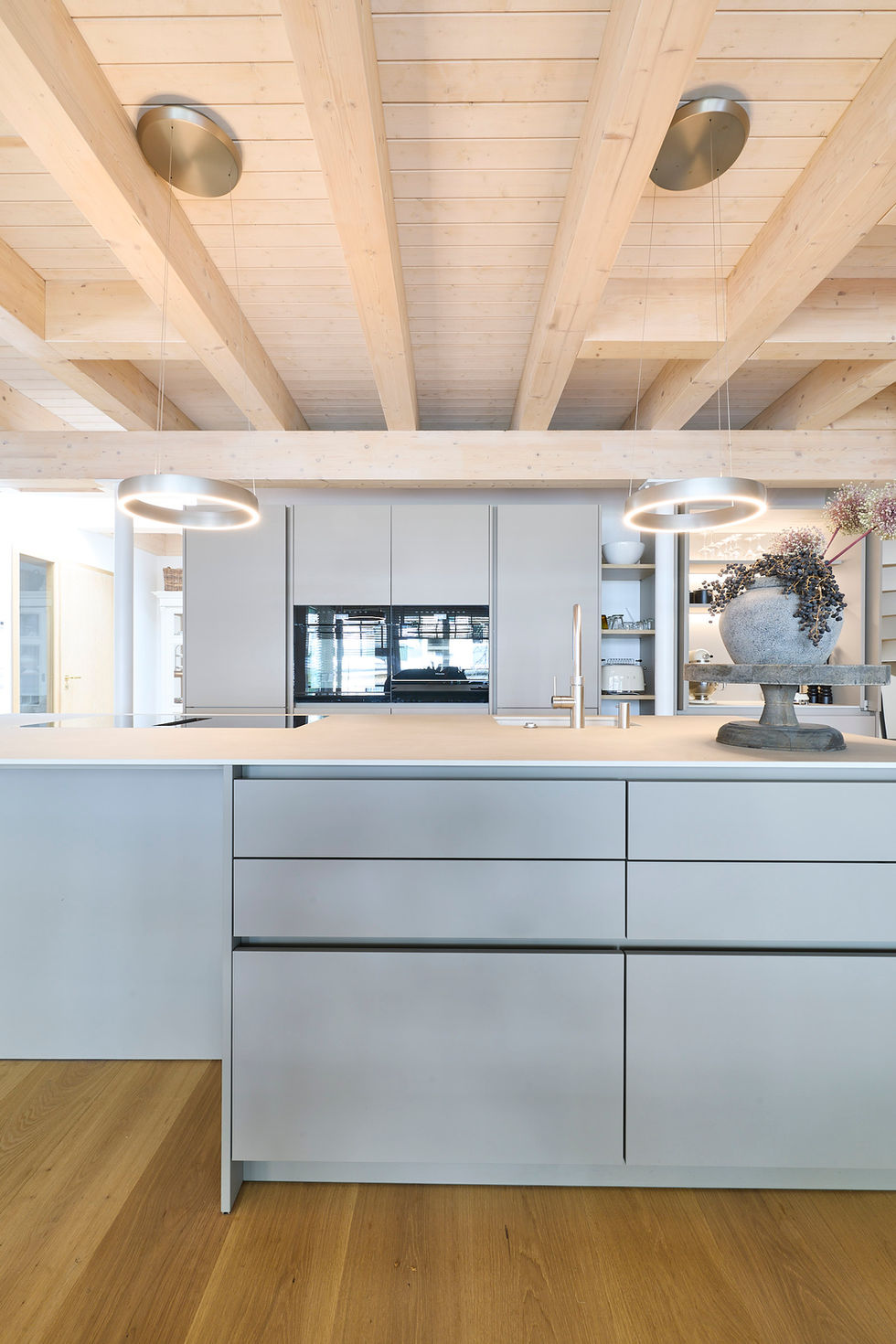 Minimalistische Designküche mit großzügiger Kochinsel, grifflosen Fronten und warmem Holz im offenen Wohnraum
