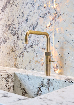 Neue Ausstellungsküche im Küchenatelier Hamburg: Transluzenter Granit ‘White Tiger’ mit hinterleuchteter Rückwand und Echtholzfronten in Davos. Die massive Insel kombiniert Licht, Struktur und natürliche Materialien zu einem modernen Küchen-Statement.