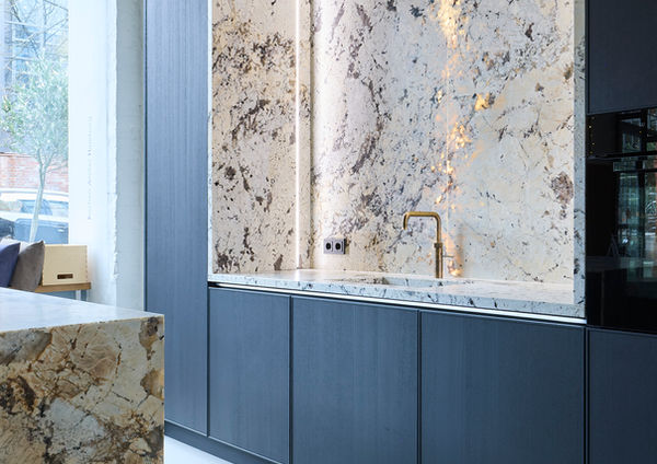 Neue Ausstellungsküche im Küchenatelier Hamburg: Transluzenter Granit ‘White Tiger’ mit hinterleuchteter Rückwand und Echtholzfronten in Davos. Die massive Insel kombiniert Licht, Struktur und natürliche Materialien zu einem modernen Küchen-Statement.