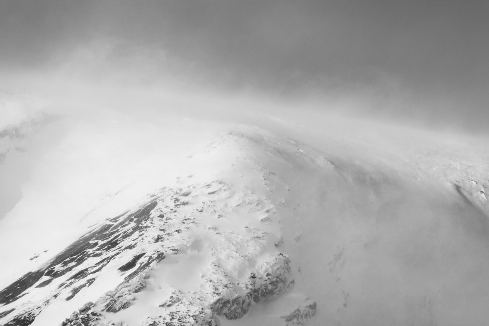 Black-and-white close-up of snowdrifts on a mountain summit.
