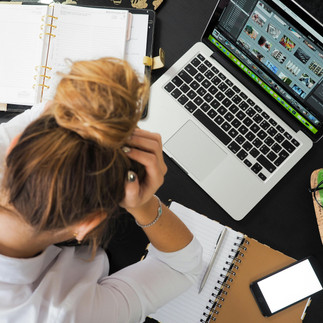 A stressed person holding their head and hair at a computer.