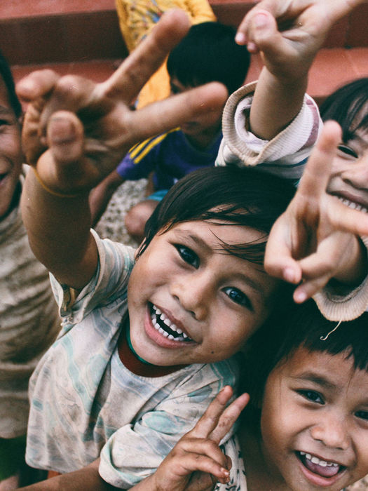 Young group of children happily looking up at the camera outside