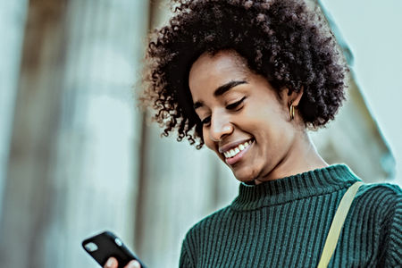Moça segurando e olhando para o celular com blusa verde