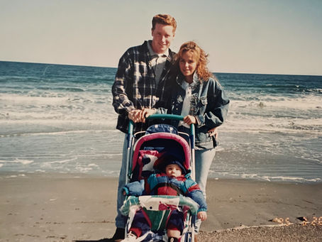 Image of a husband and a wife with a baby at the beach.